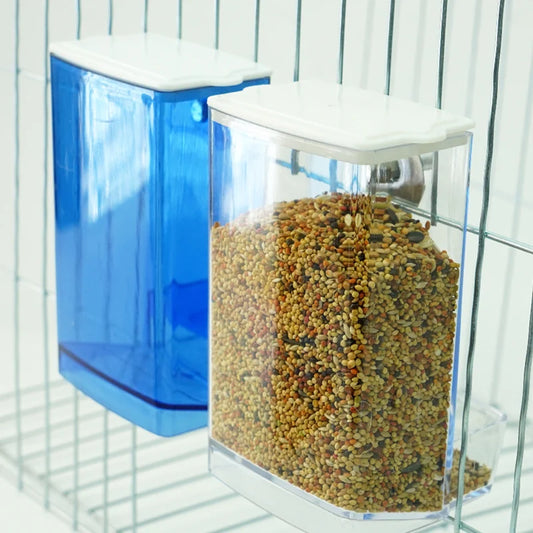 Clear automatic bird feeder mounted inside bird cage – filled with seeds